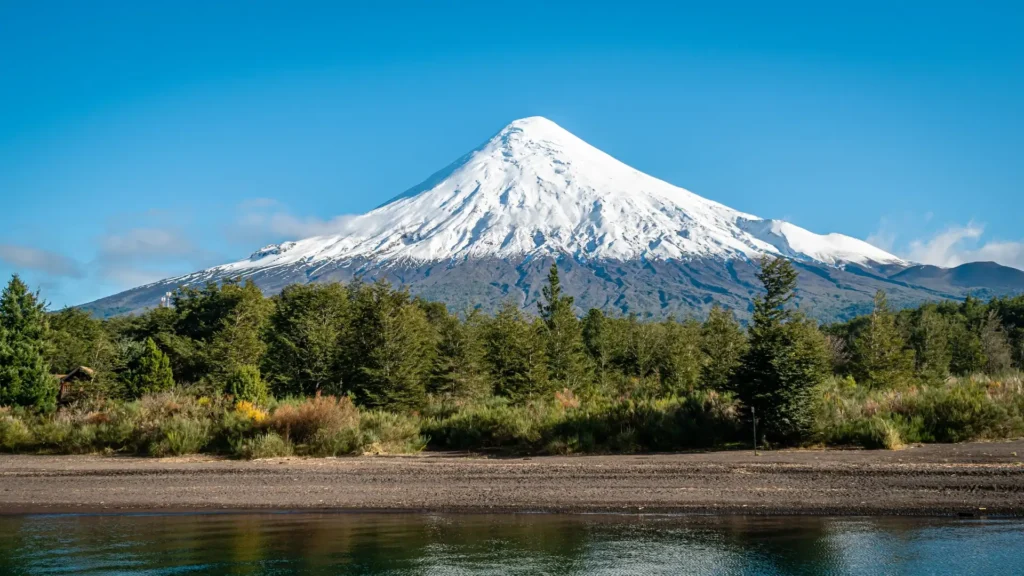 Snow-capped volcano seen from Puerto Montt, with native forest and water in the foreground, Chile