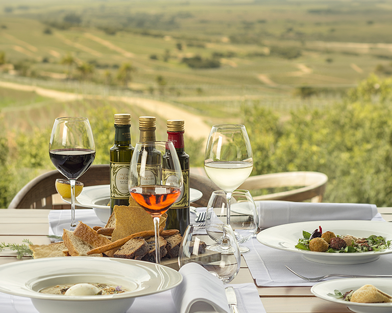 Table with wine glasses and dishes served in front of the vineyards of Bodega Garzón, Uruguay