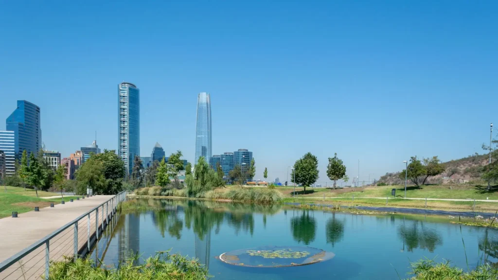 Urban park with lagoon and vegetation, with the Great Coastal Tower in the background, in Santiago de Chile
